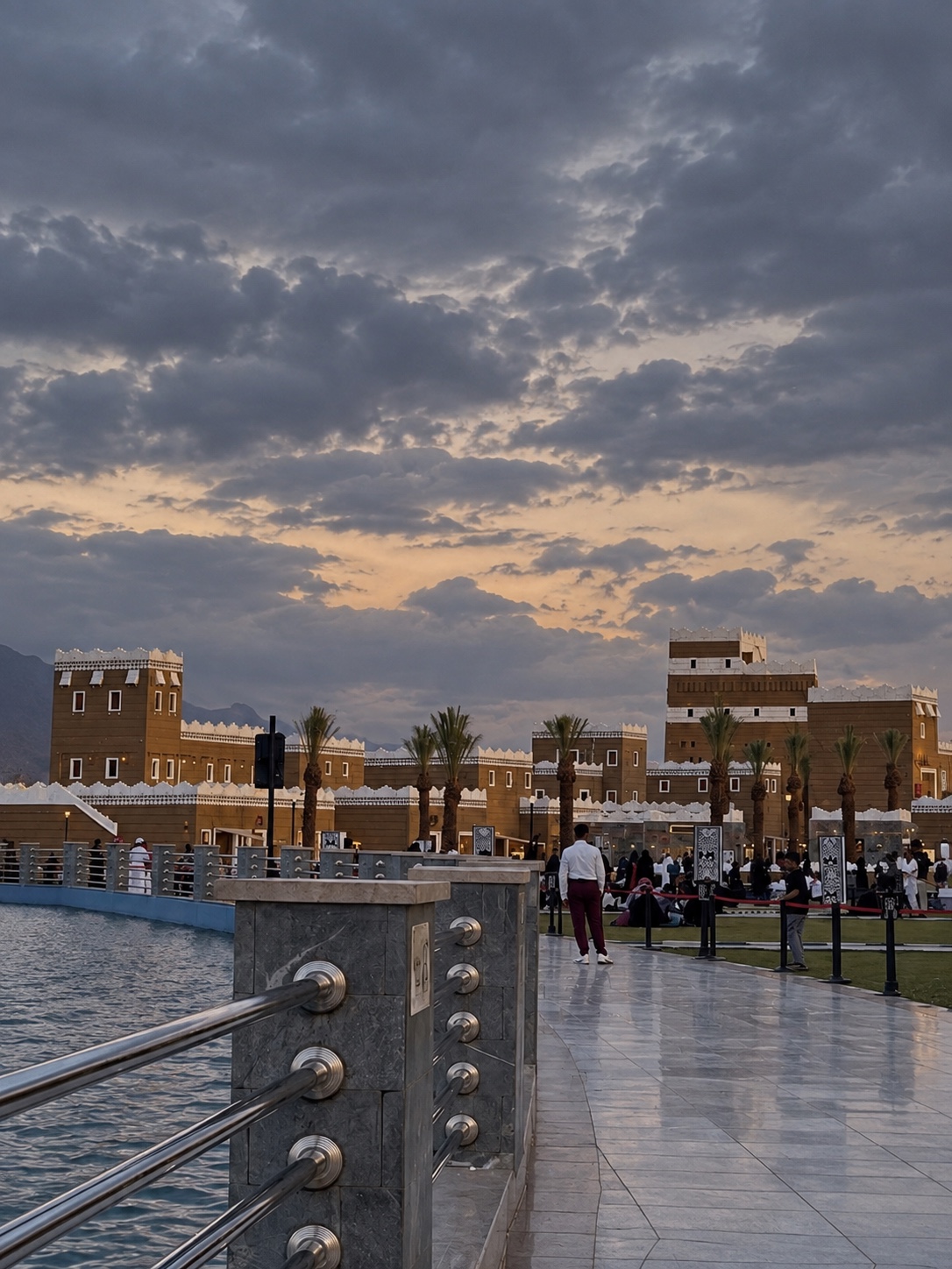 ممشى المنتجع على ضفاف الماء تحت غيوم المساء وأمام المباني التراثية
